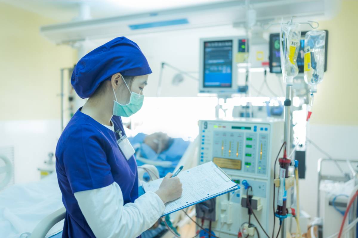 A nephrology nurse practitioner checks the monitor of a renal replacement therapy patient.