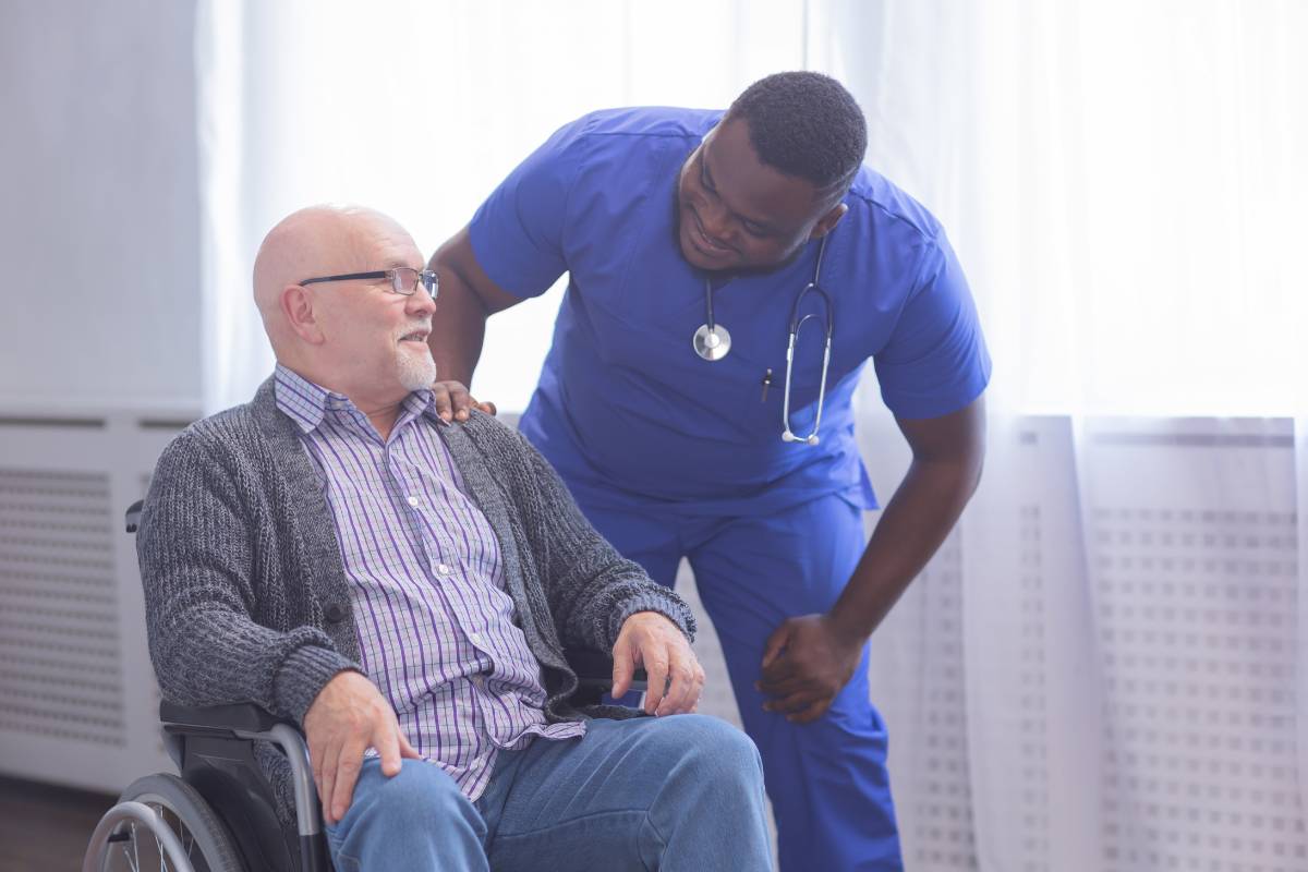 A nephrology nurse speaks with a patient in a wheelchair.