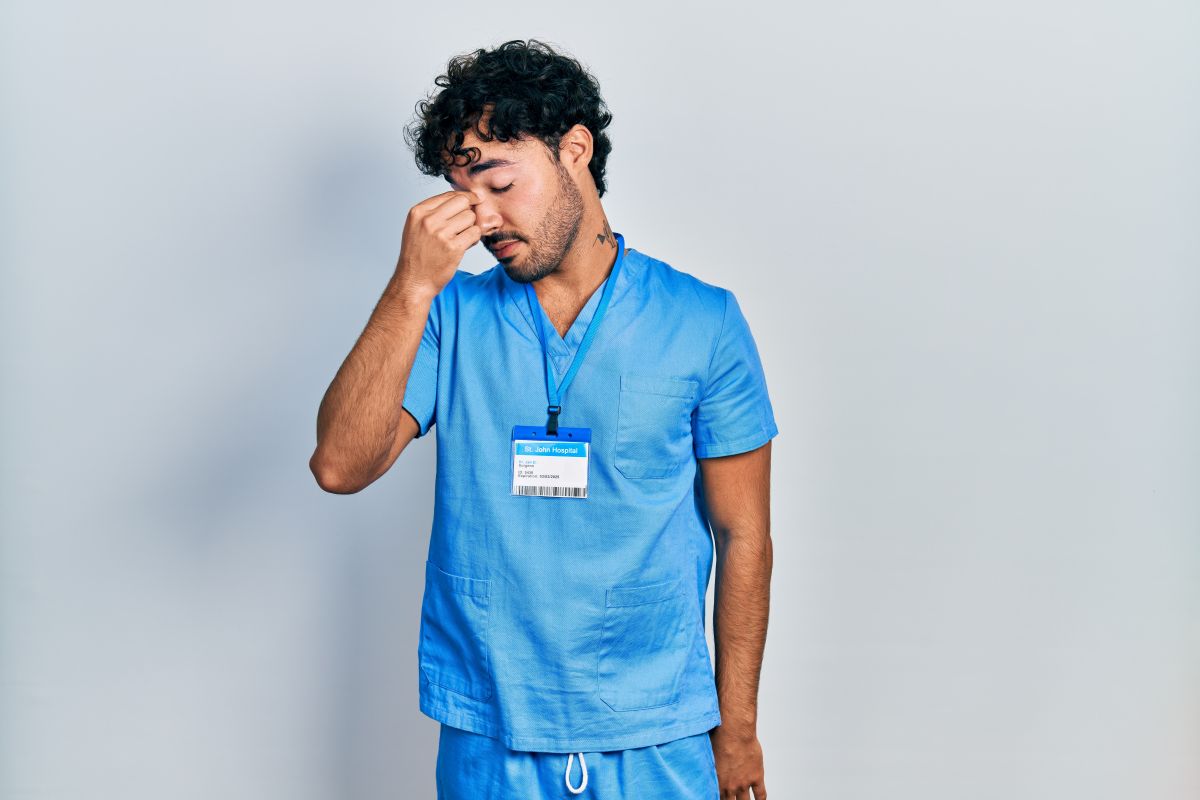 An RN dealing with nurse fatigue rubs his eyes.