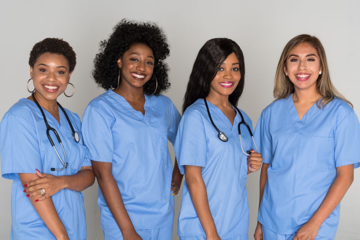 Four nurses standing and smiling at the camera.