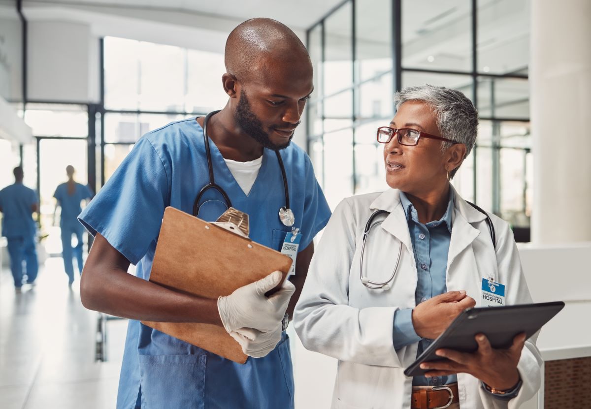 A nurse checking in with his nurse manager in the hallway of a hospital.