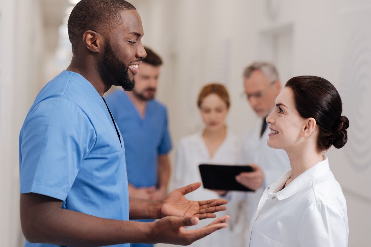 Two nurses who are part of a nurse mentorship program talking in the hallway.