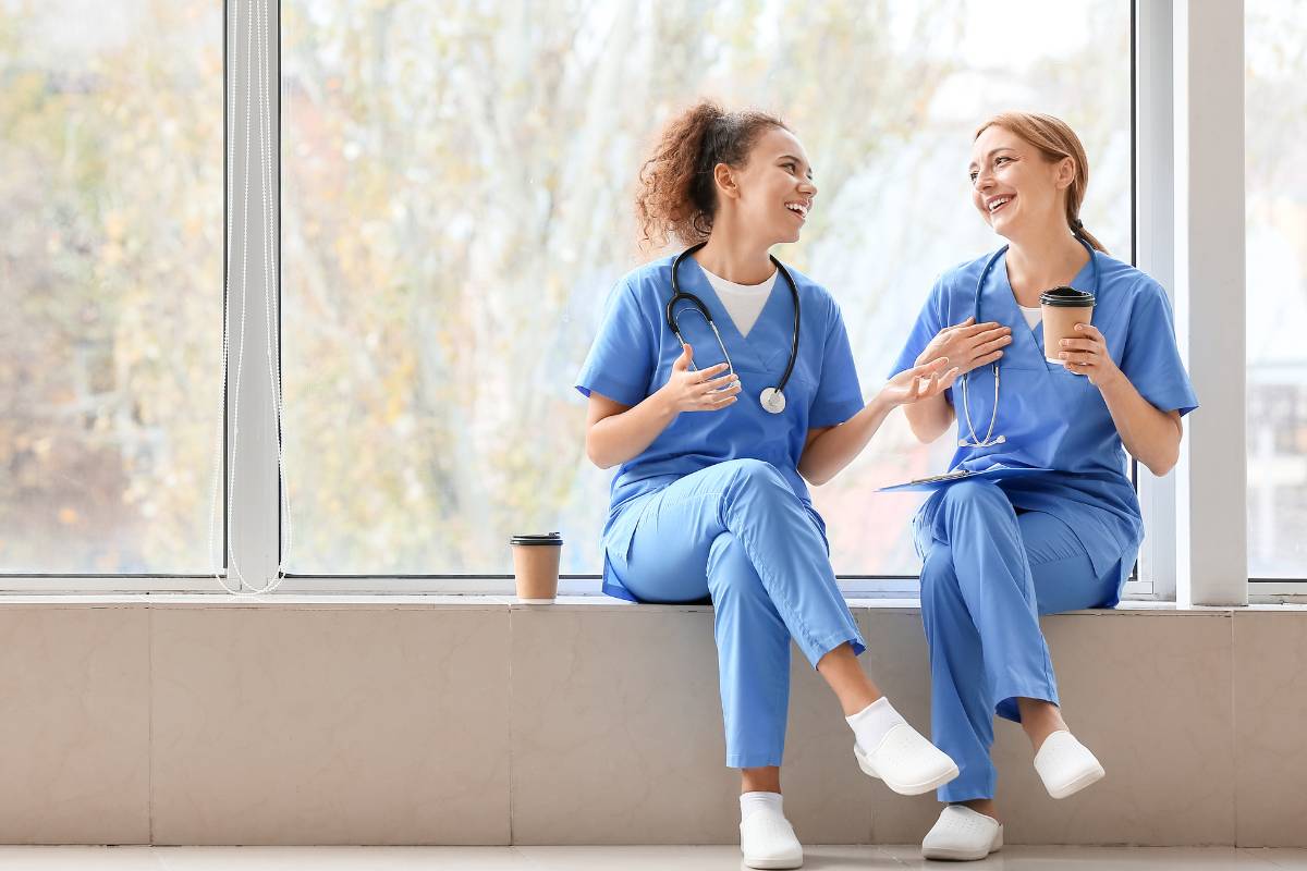 Two nurses enjoy Nurses Week freebies of coffee and snacks before their shift.