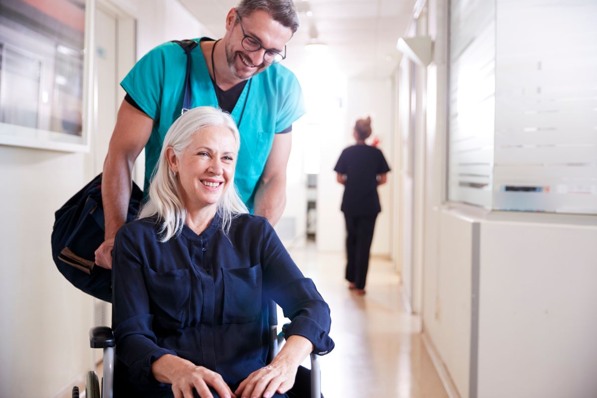 A nurse helps his patient to the door after giving her a nursing discharge note.