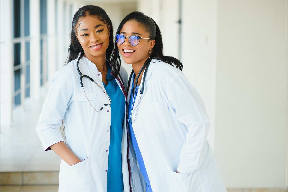 Two female nurses in white coats at a nursing pinning ceremony.