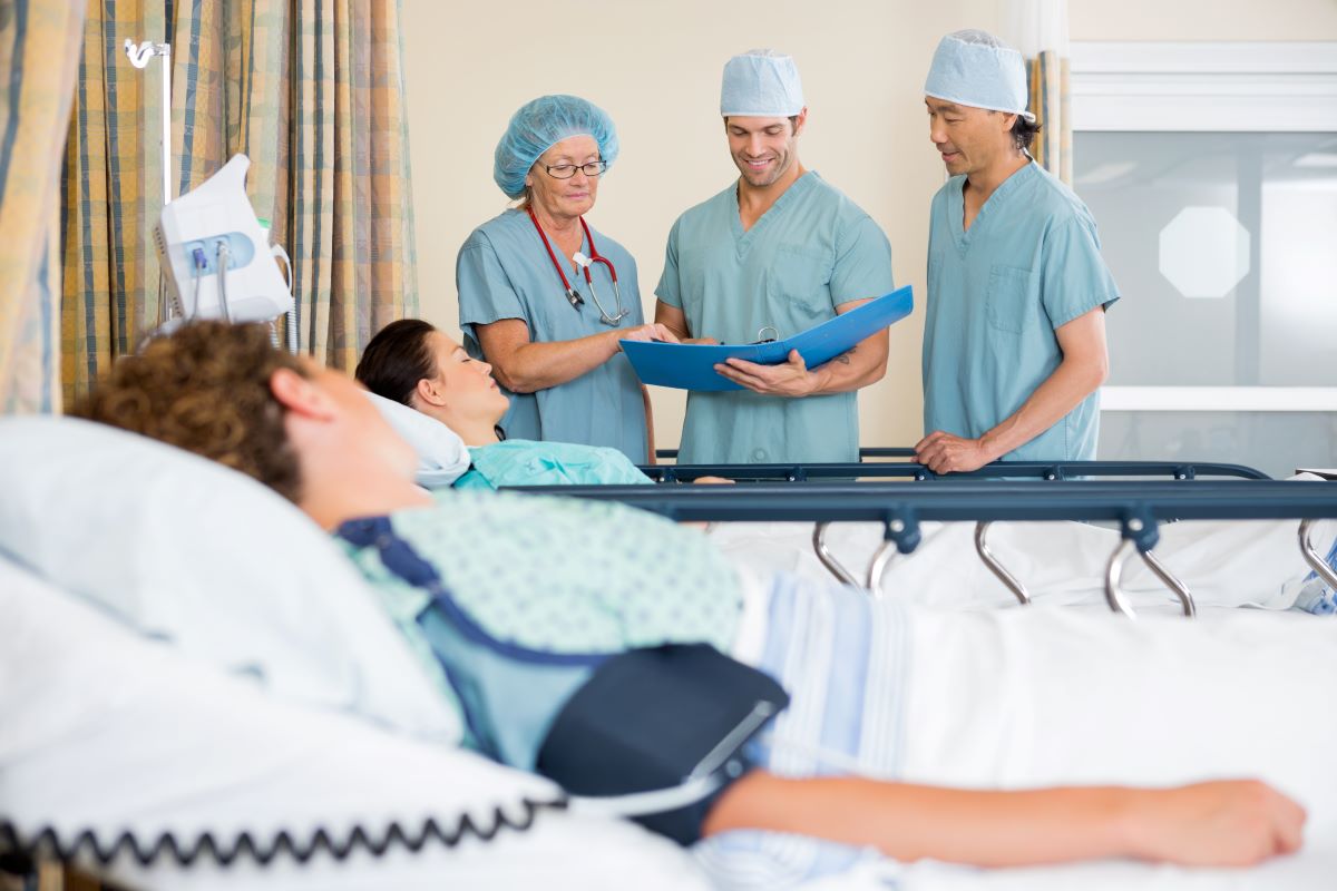 A team of PACU nurses looks pleased as they check a recovering patient's chart.