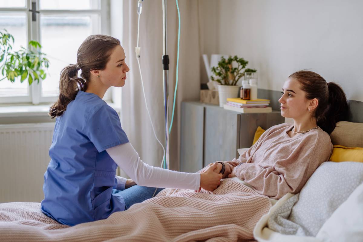 A pediatric psych nurse speaks with an adolescent patient in an inpatient facility.