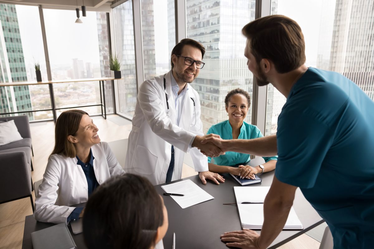 A newly hired nurse, who was selected using predictive hiring methods, shakes the hand of a new colleague.