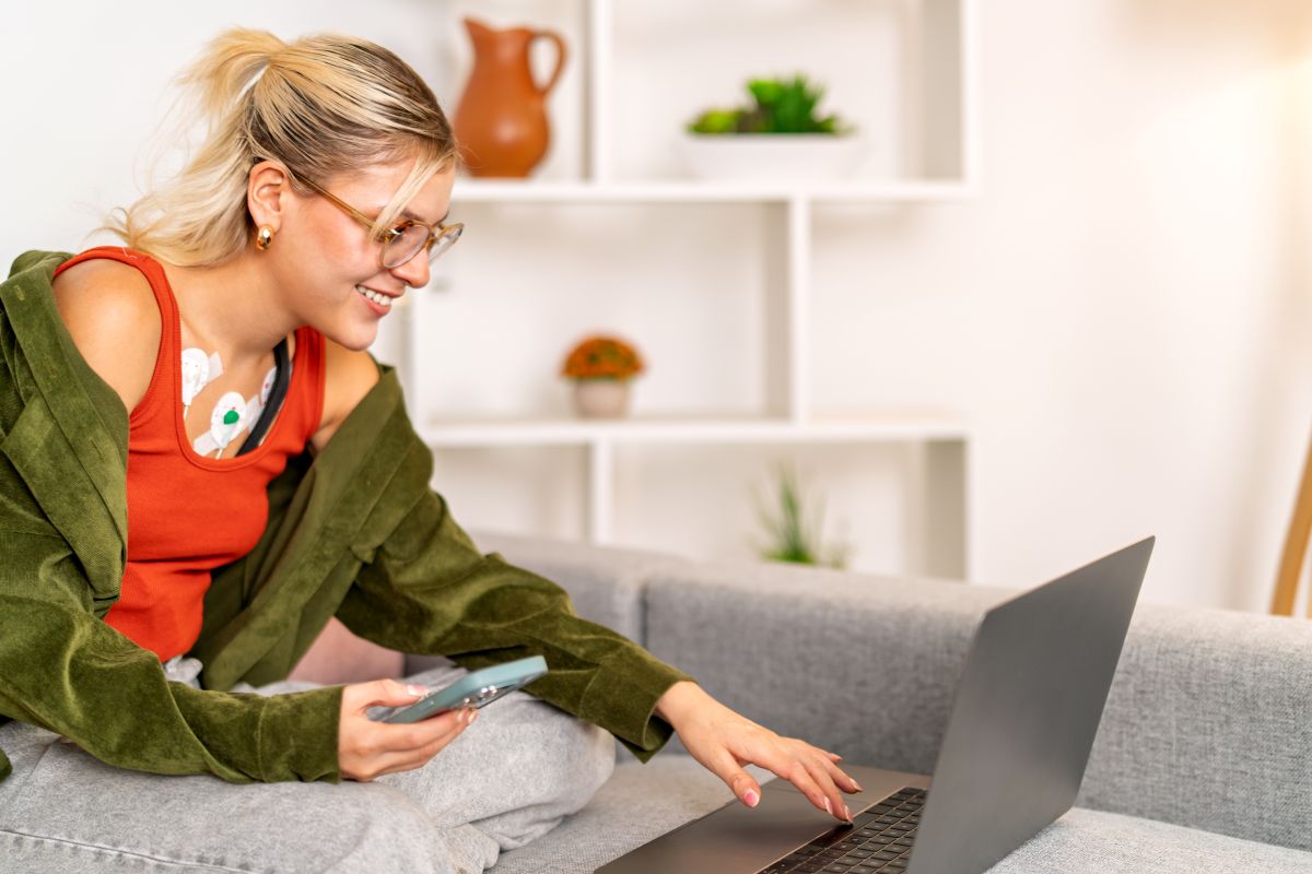 A woman with electrodes on her body uploads data to her physician, illustrating remote patient monitoring.