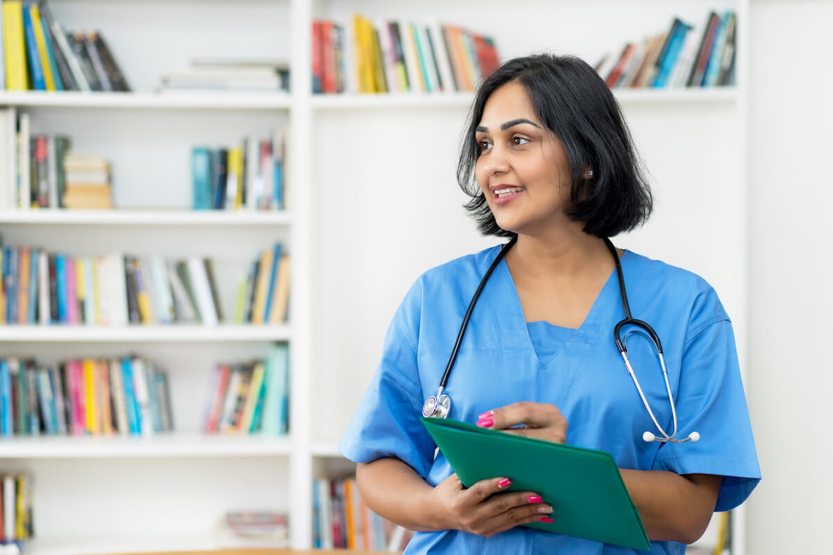 RN case manager in blue scrubs holding a clipboard.