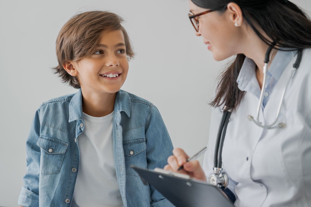 A school nurse asks a student questions and writes down answers on her clipboard.