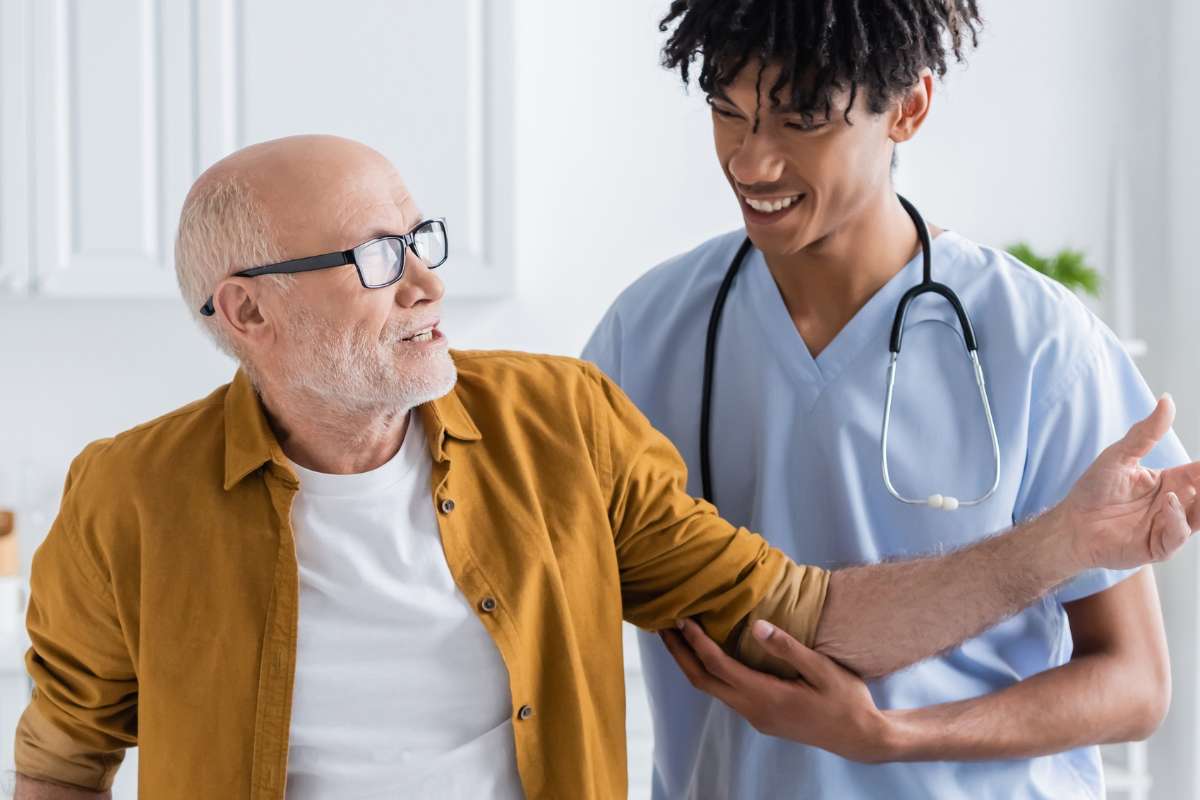African-American male nurse using Tanner's clinical judgment model to examine an elder white male patient.