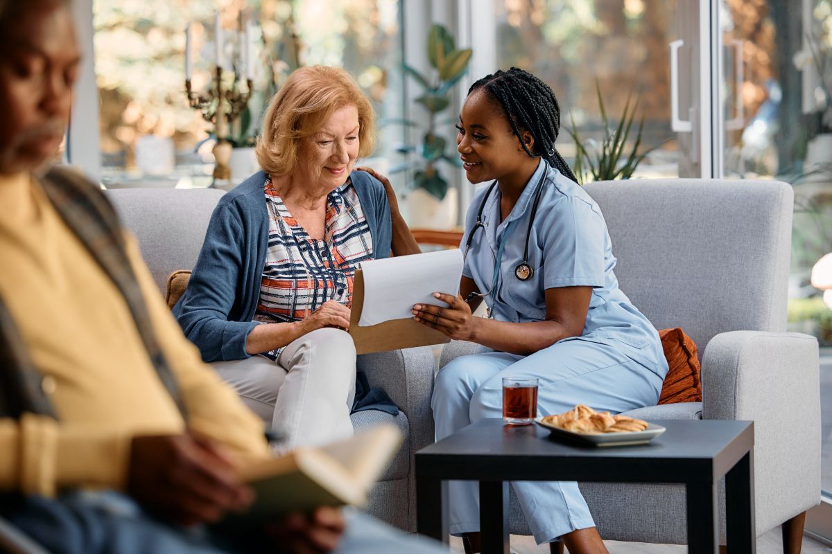 The leader of a team at a skilled nursing facility sits down with a patient.