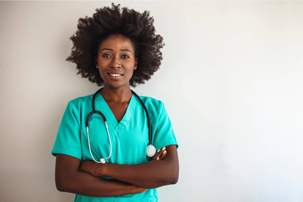 A travel LPN poses for a photo while smiling and wearing teal scrubs.