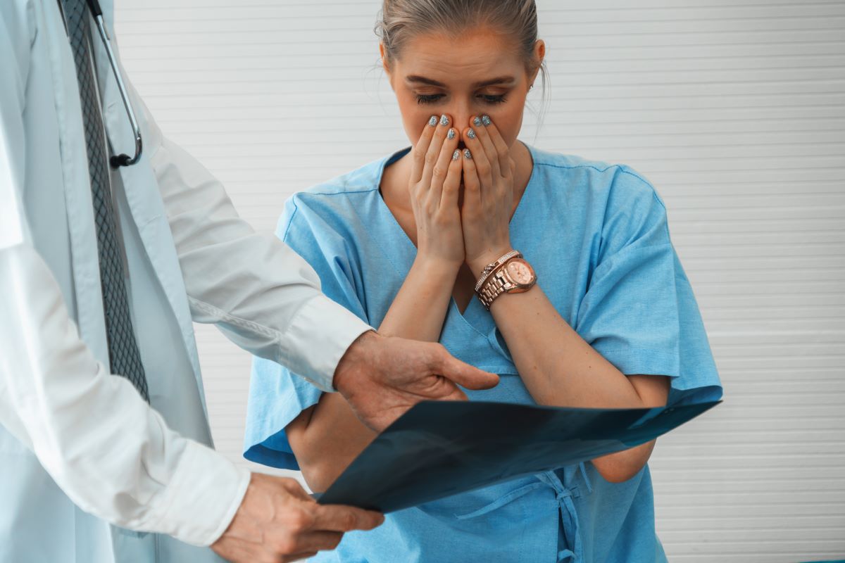A physician points out an error to a nurse, who looks aghast.