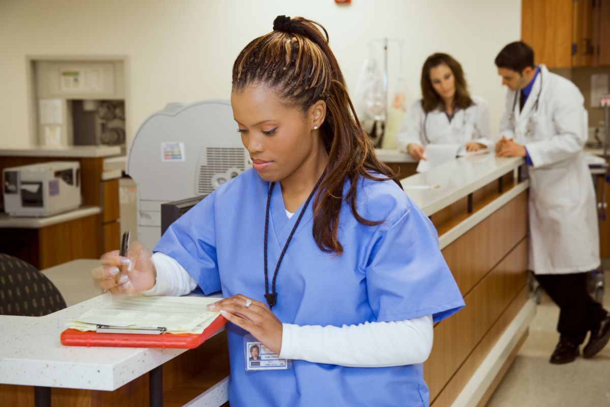 A nurse writes information on a patient chart.