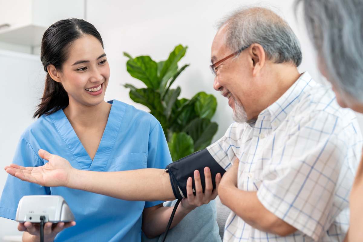 Female medical assistant taking blood pressure of an elder male patient.