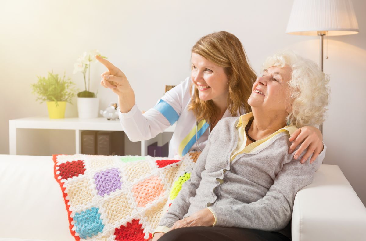A woman points to a camera in the room she's showing to her mother, who is a nursing home resident.