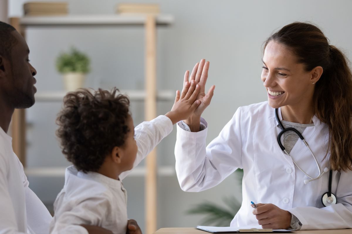 A doctor high-fives a young patient.